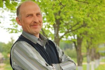 portrait of mature smiling man with crossed hands outdoor