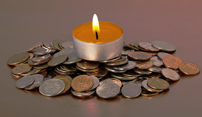 The decorative candle burns on a pyramid from coins