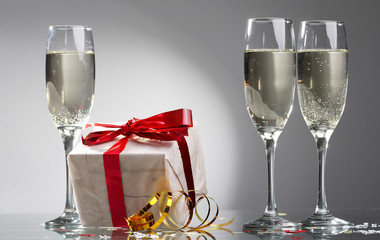 Glasses of champagne, gifts with red tapes and bows