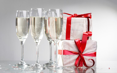 Glasses of champagne, gifts with red tapes and bows