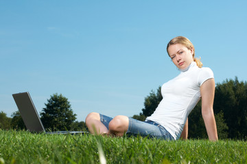 The girl with laptop on a green lawn