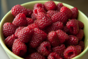 frische rote reife Himbeeren in einer grünen Schüssel