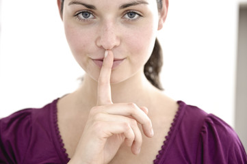 junge schöne frau legt geheimnisvoll finger auf lippen