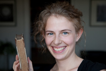 unge blonde Frau mit Buch in Hand, lächelnd