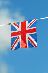 Small england flag against blue sky