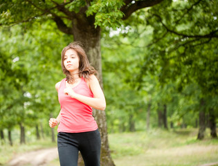 Naklejka na ściany i meble Woman jogging through a forest