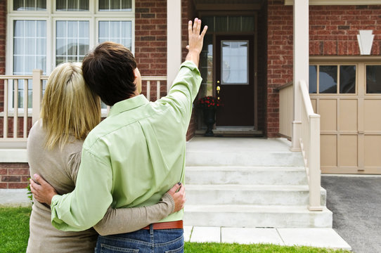 Happy couple in front of home