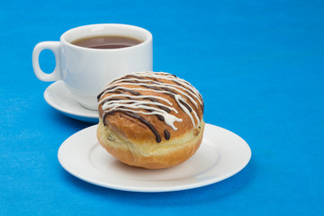 Donut  with chocolate and sugar glaze. Cup tea.