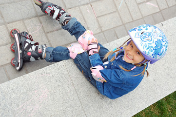 child with rollerskates and protective helmet and pads