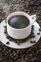 Hot coffee cup on the beans. Close up