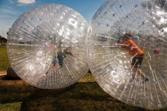 Kind hat Spass in einer Zorbing Kugel und freut sich
