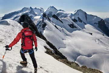 Papier Peint photo Alpinisme Mountaineer walks down along a snowy ridge