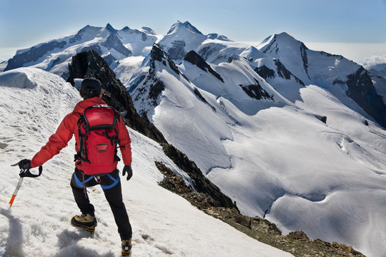 Mountaineer walks down along a snowy ridge