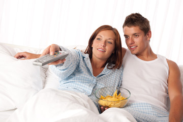 Obraz na płótnie Canvas Młoda kobieta i mężczyzna w łóżku oglądając telewizję