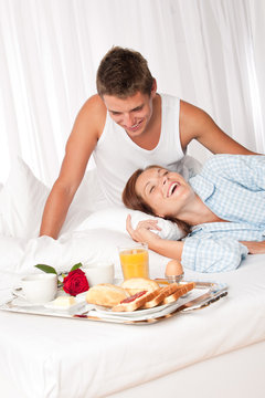Young smiling couple having luxury breakfast in hotel room