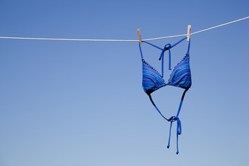 Blue bikini top hanging on a clothesline