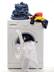 Waschmaschine mit Kleidung, die in weiße, farbige und dunkle Jeans getrennt, freigestellt auf einem weißen Hintergrund getrennt ist