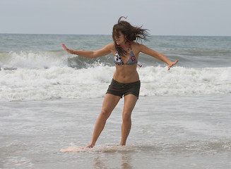 Teen girl skim boarding at the beach.