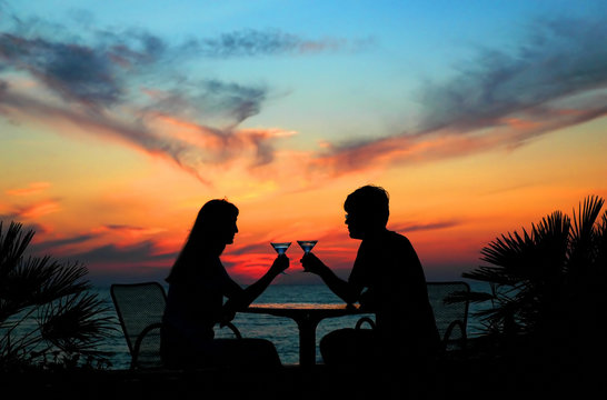 The pair silhouette is held by goblet on a sundown