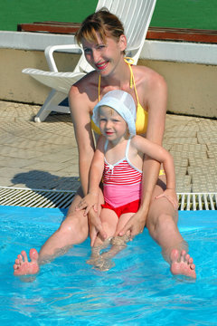 The woman and the little girl sit at pool