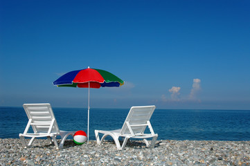 Two chaise lounges and umbrella on a beach