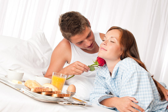 Happy man and woman having breakfast in bed together
