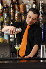Bartender pouring a green cocktail.