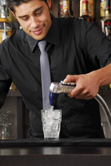 Bartender pouring soda on a drink.