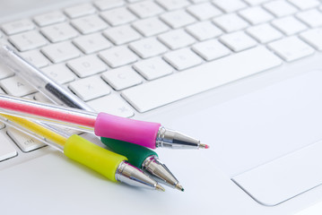 Colorful pens on white laptop keyboard