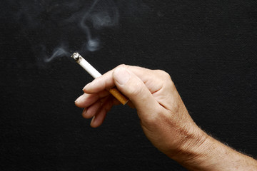 Male hand holding smoking cigarette