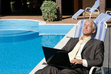 Businessman with laptop computer resting on deckchair
