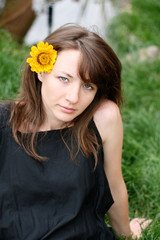 beautiful woman sitting on a green grass. Looking in camera