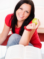 smiling brunette woman holding an apple and studying