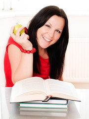 smiling brunette woman holding an apple and studying