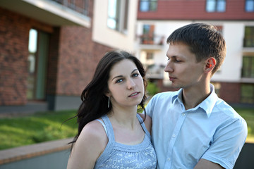 Couple in front of house in modern residential area.