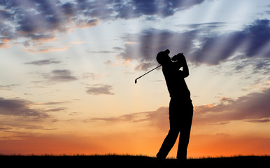 Golfer silhouetted against beautiful sunrise
