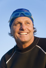 A happy smiling forties wearing wetsuit,cap and goggles.