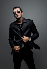 attractive young man wearing elegant black suit and sunglasses