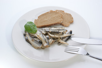 some sprats and bread on a white plate