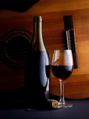 glass of wine and a bottle with a guitar as a background