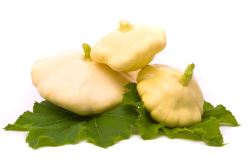 Scallop squash and green leaves on white background