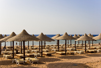 A sunny tropical beach with straw umbrella