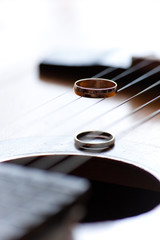 Two wedding rings are on guitar stripes