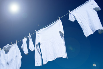weiße wäsche vor sonnigem und blauem himmel