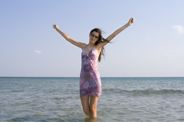 Fototapeta na wymiar beautiful young girl in sunglasses standing in the sea