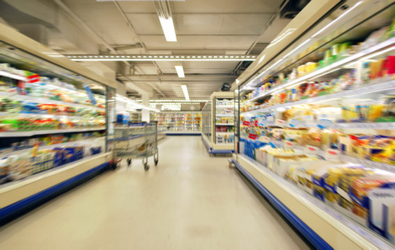 blurred supermarket shelves and aisle with trolley