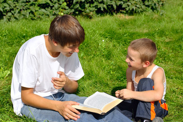 The happy teenager and kid with a book