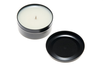 A candle in a black metal can with the lid off