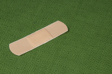 A single band aid on a green background.