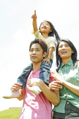 娘を肩車する父親とそばに立つ母親